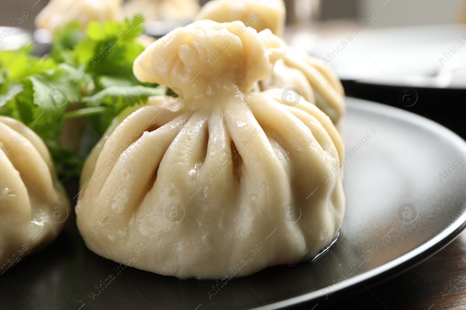 Photo of Delicious khinkali served with cilantro on wooden table, closeup