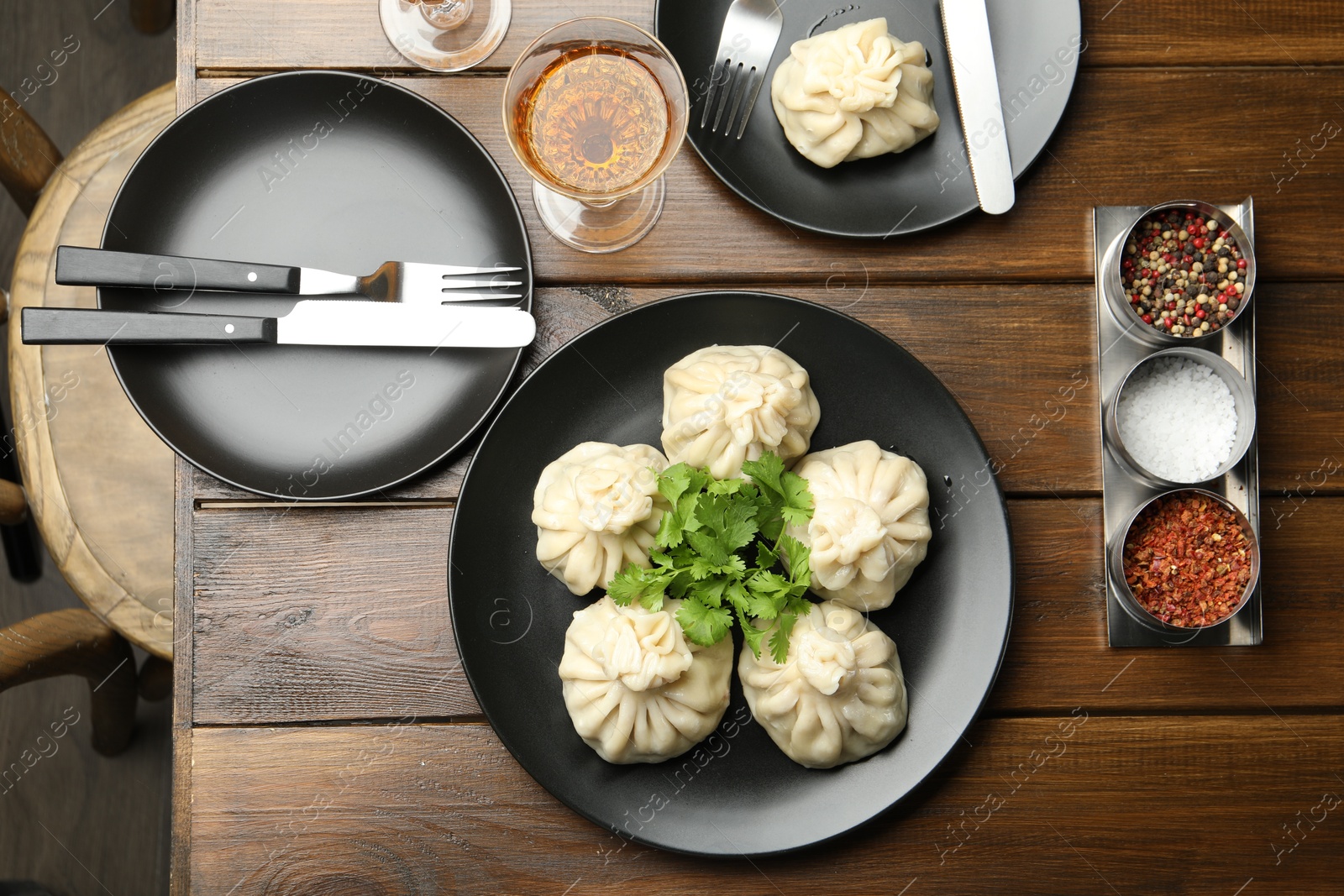 Delicious khinkali served with cilantro and wine on wooden table, flat lay Photo of Delicious khinkali served with cilantro and wine on wooden table, flat lay