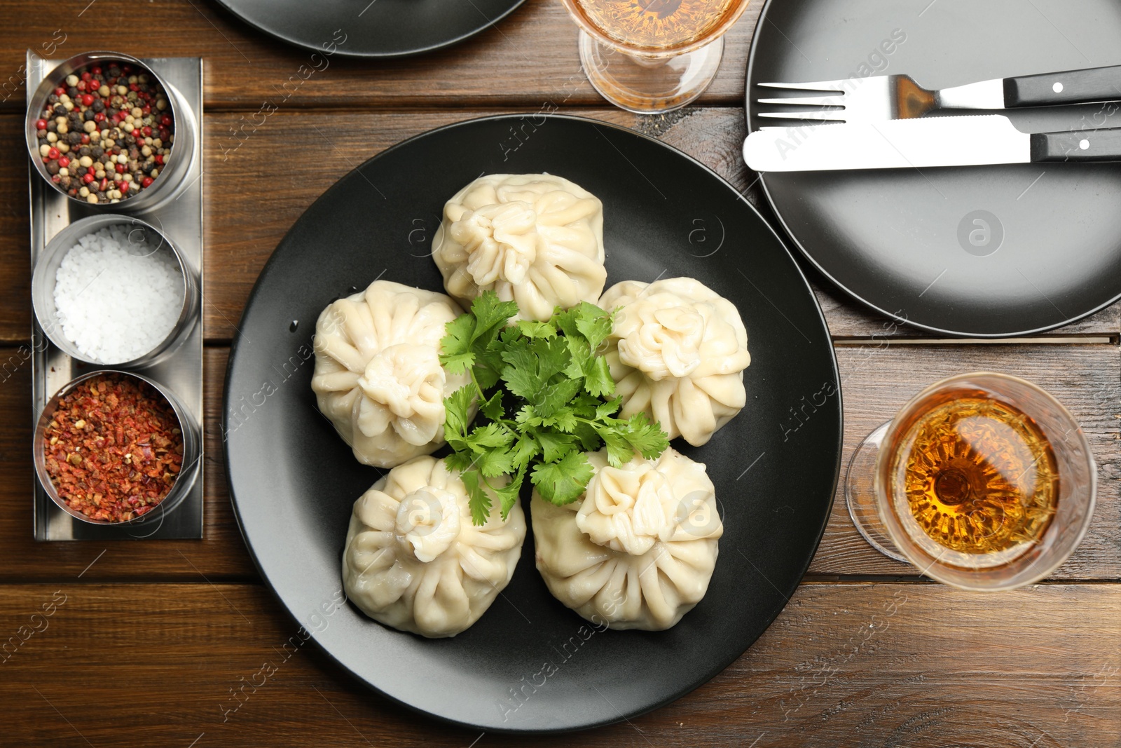 Delicious khinkali served with cilantro and wine on wooden table, flat lay Photo of Delicious khinkali served with cilantro and wine on wooden table, flat lay