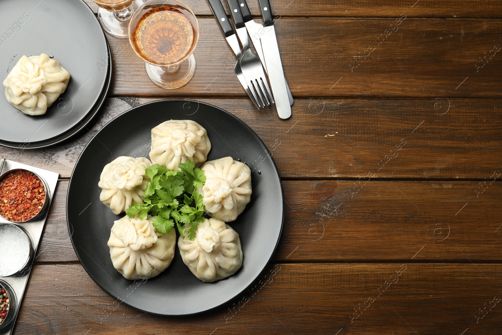 Photo of Delicious khinkali served with cilantro and wine on wooden table, flat lay. Space for text