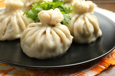 Photo of Delicious khinkali served with cilantro on table, closeup