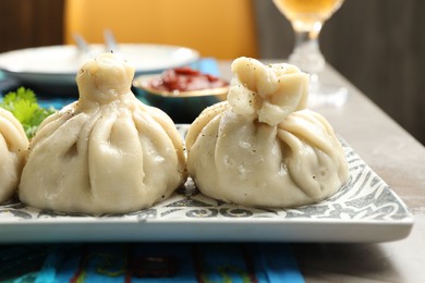 Photo of Delicious cooked khinkali served with sauce on grey table, closeup
