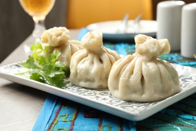 Photo of Delicious khinkali served with cilantro on grey table, closeup