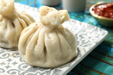 Photo of Delicious khinkali served with sauce on table, closeup