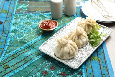 Photo of Delicious khinkali served with sauce and cilantro on grey table, space for text