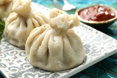 Photo of Delicious khinkali served with sauce on table, closeup