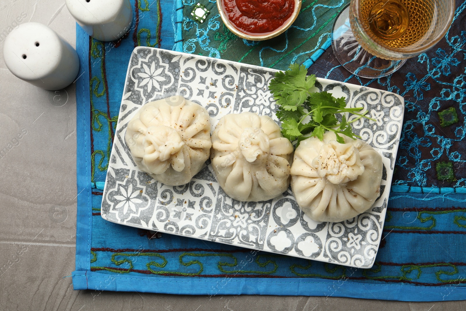 Delicious khinkali served with sauce and cilantro on grey table, flat lay Photo of Delicious khinkali served with sauce and cilantro on grey table, flat lay