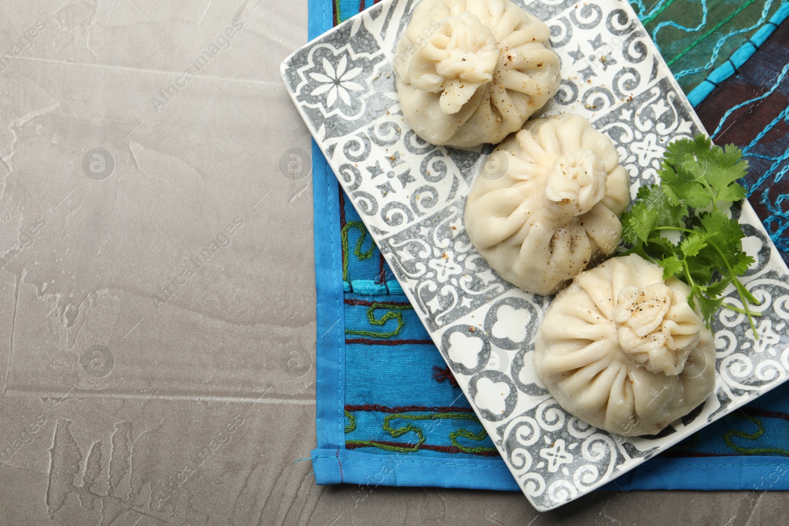 Delicious khinkali served with cilantro on grey table, top view. Space for text Photo of Delicious khinkali served with cilantro on grey table, top view. Space for text