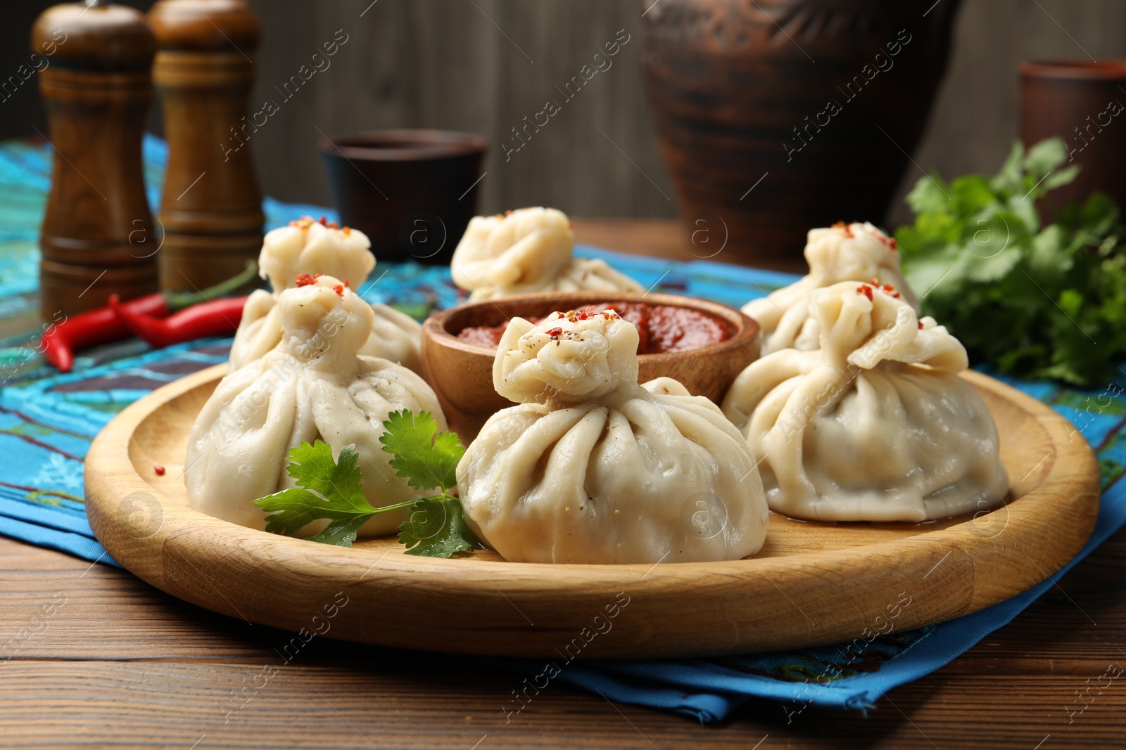 Delicious khinkali served with sauce on wooden table, closeup Photo of Delicious khinkali served with sauce on wooden table, closeup