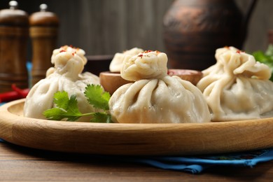 Photo of Delicious khinkali served with sauce on wooden table, closeup