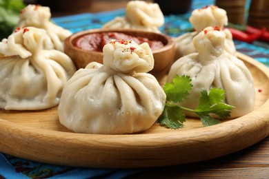 Photo of Delicious khinkali served with sauce on wooden table, closeup