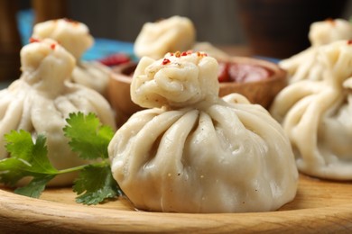 Photo of Delicious khinkali served with sauce on wooden plate, closeup