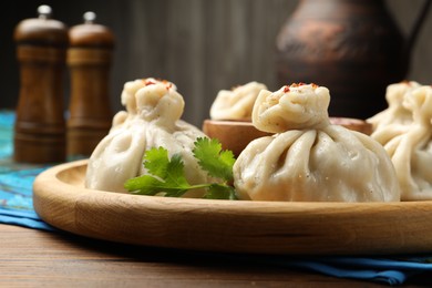 Photo of Delicious khinkali served with sauce on wooden table, closeup