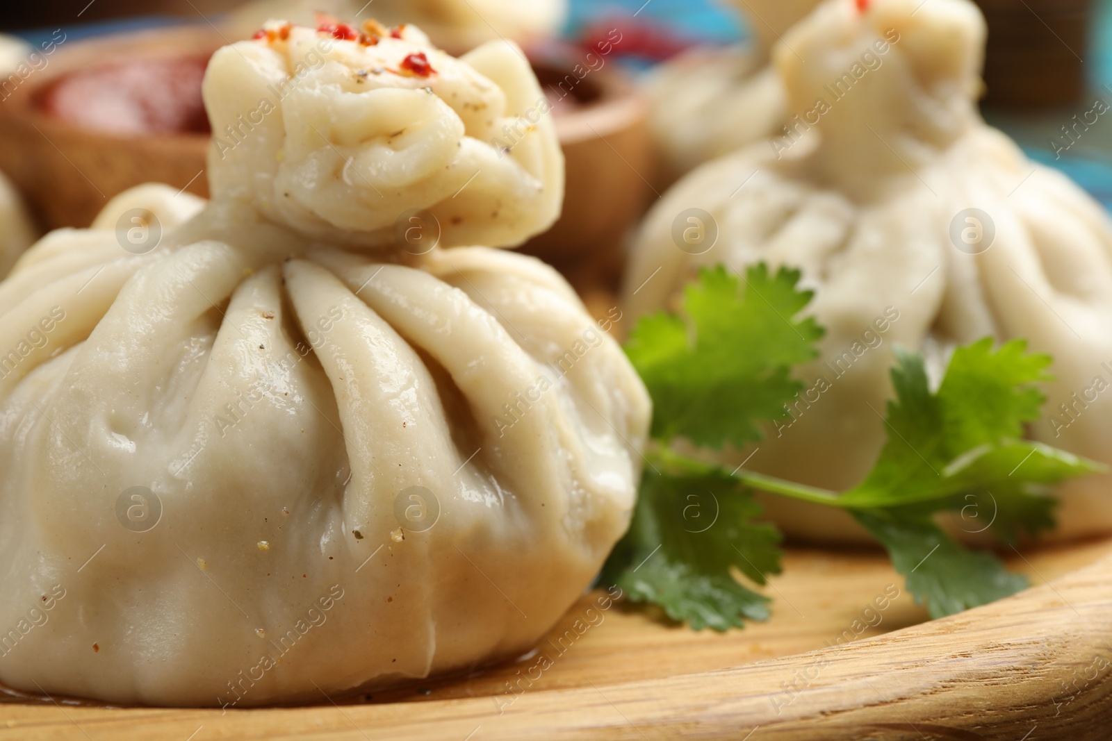 Delicious khinkali served with sauce on wooden plate, closeup Photo of Delicious khinkali served with sauce on wooden plate, closeup