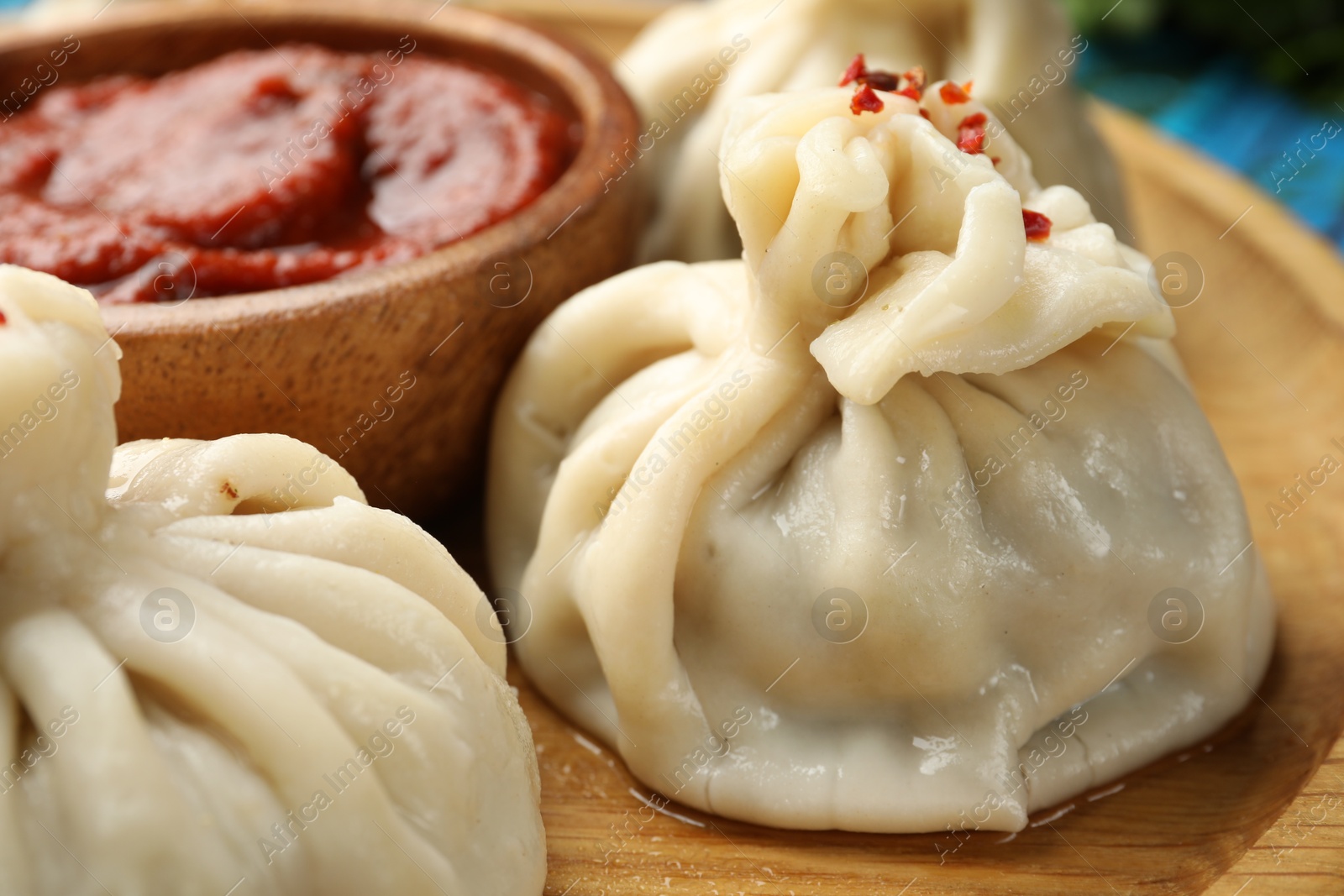 Delicious khinkali served with sauce on wooden plate, closeup Photo of Delicious khinkali served with sauce on wooden plate, closeup