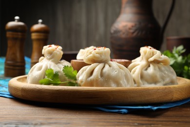 Photo of Delicious khinkali served with sauce on wooden table, closeup