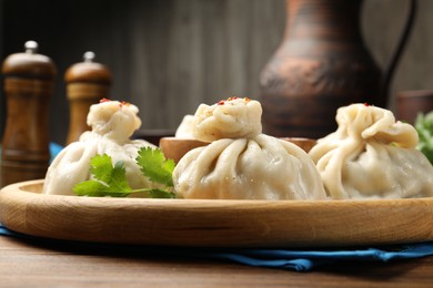Photo of Delicious khinkali served with sauce on wooden table, closeup
