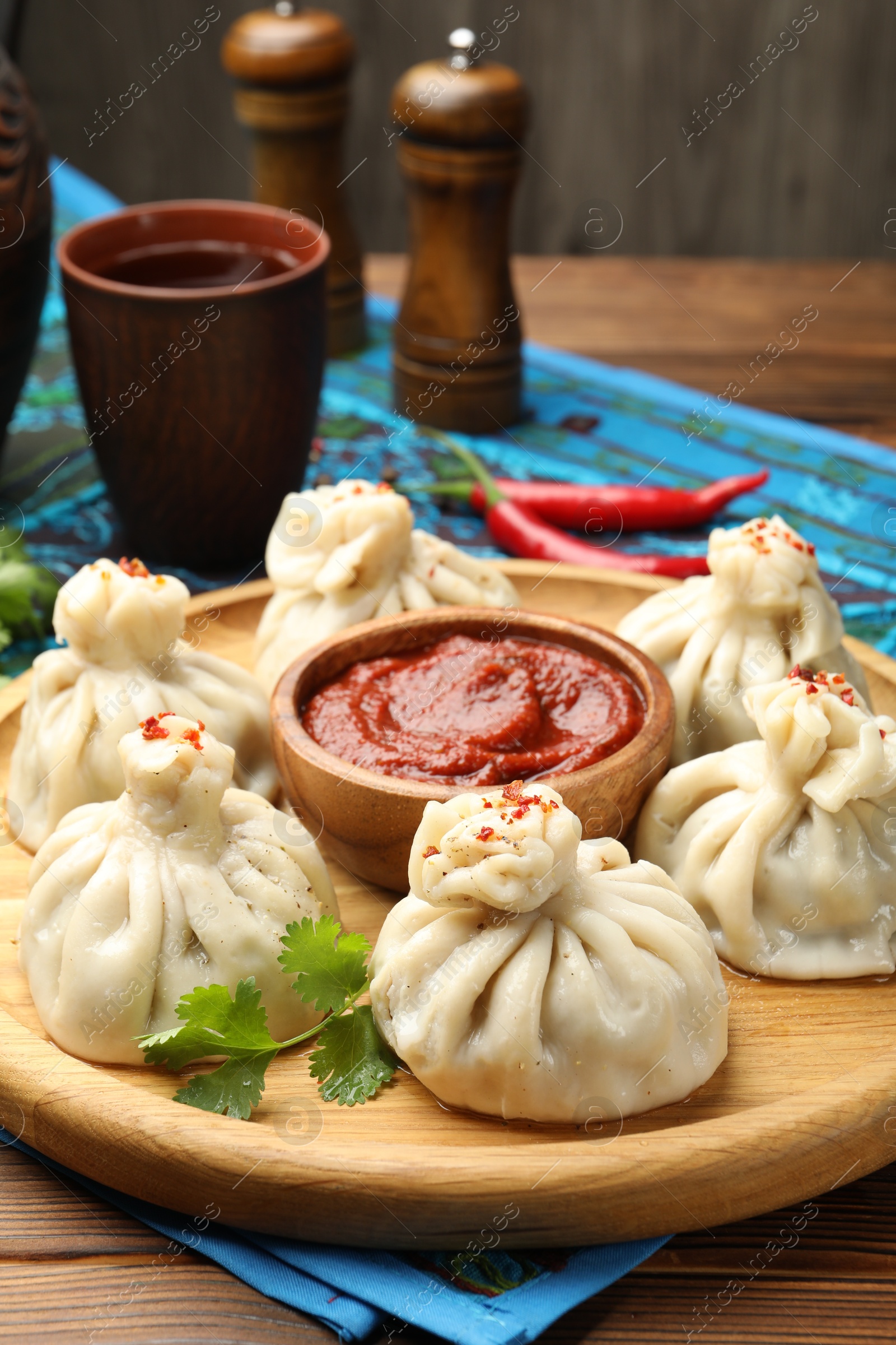 Delicious khinkali served with sauce on wooden table, closeup Photo of Delicious khinkali served with sauce on wooden table, closeup