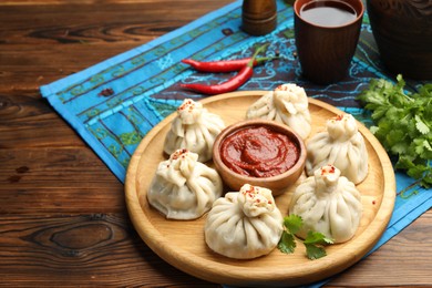 Photo of Delicious khinkali served with sauce on wooden table