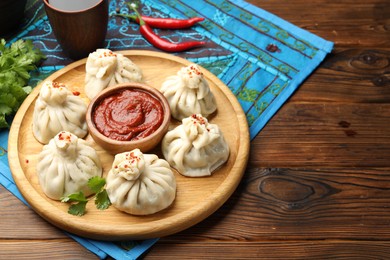 Photo of Delicious khinkali served with sauce on wooden table
