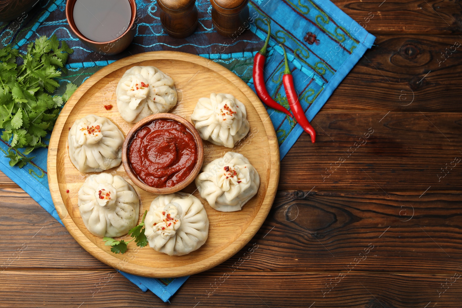 Delicious khinkali served with sauce on wooden table, flat lay Photo of Delicious khinkali served with sauce on wooden table, flat lay