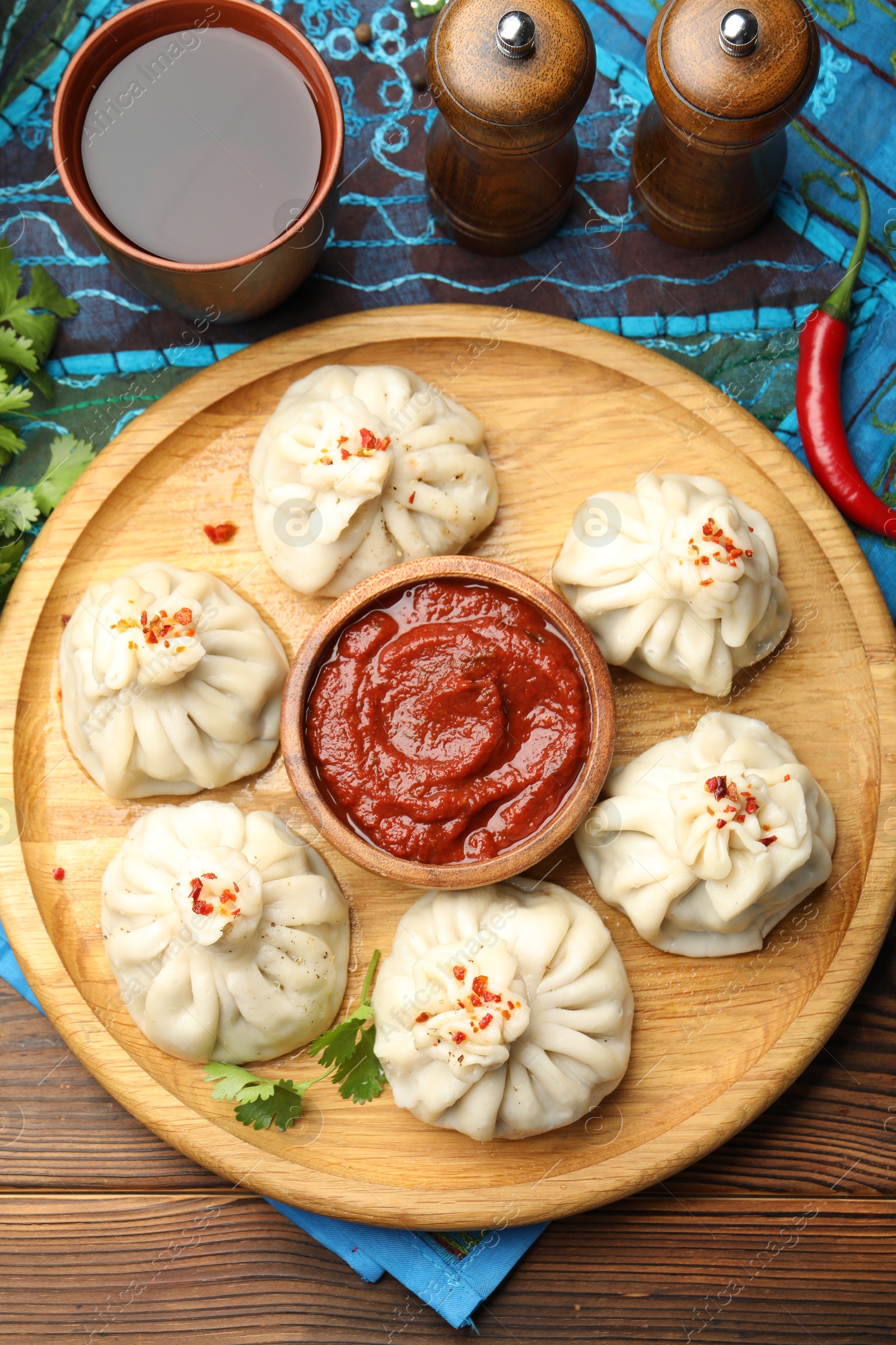 Delicious khinkali served with sauce on wooden table, flat lay Photo of Delicious khinkali served with sauce on wooden table, flat lay