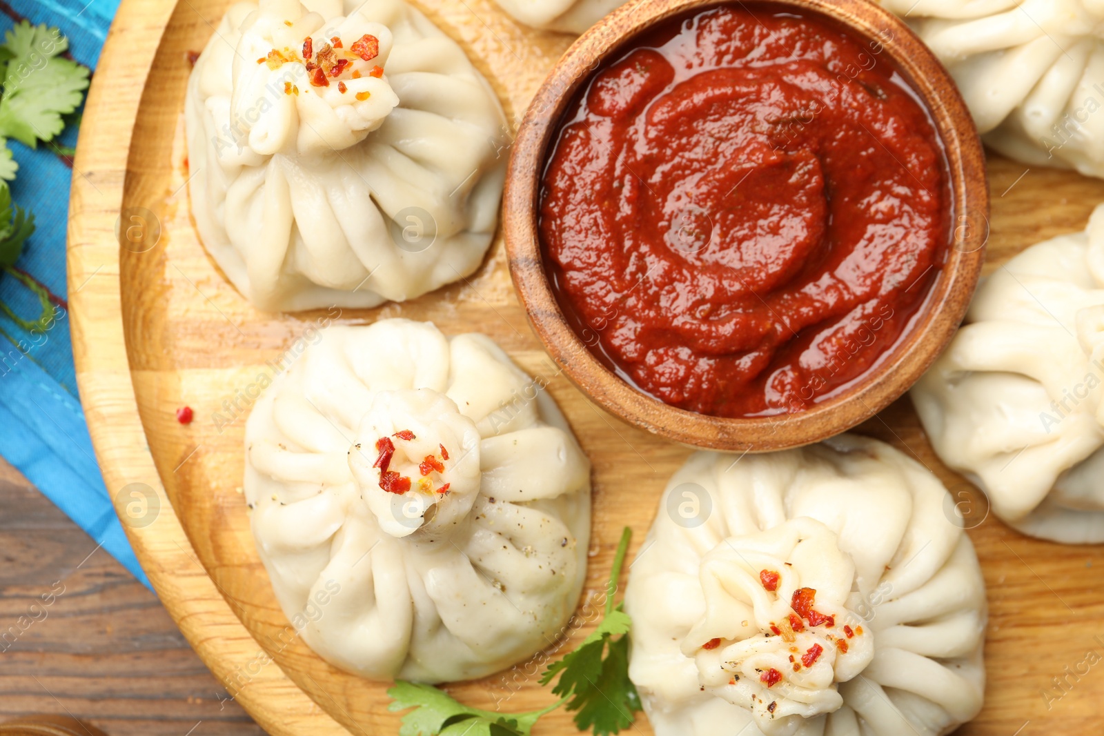 Delicious khinkali served with sauce on wooden table, top view Photo of Delicious khinkali served with sauce on wooden table, top view