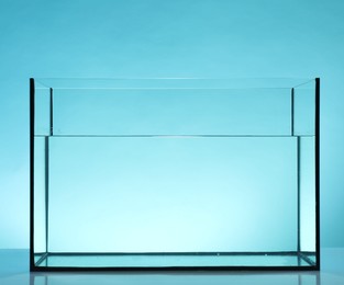 Photo of Glass aquarium with water on table against light blue background