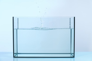 Photo of Glass aquarium with splashing water on light background