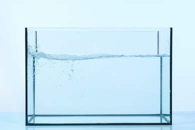 Photo of Glass aquarium with splashing water on light background