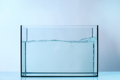 Photo of Glass aquarium with splashing water on light background