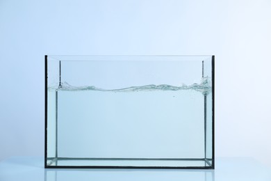 Photo of Glass aquarium with splashing water on light background