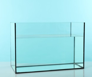 Photo of Glass aquarium with water on white table against turquoise background