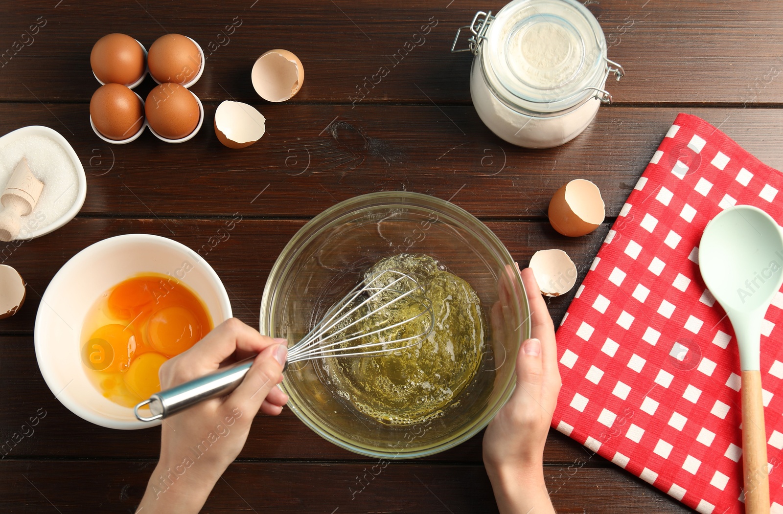 Woman whisking egg whites in bowl at wooden table, top view Photo of Woman whisking egg whites in bowl at wooden table, top view