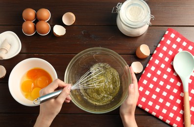 Photo of Woman whisking egg whites in bowl at wooden table, top view