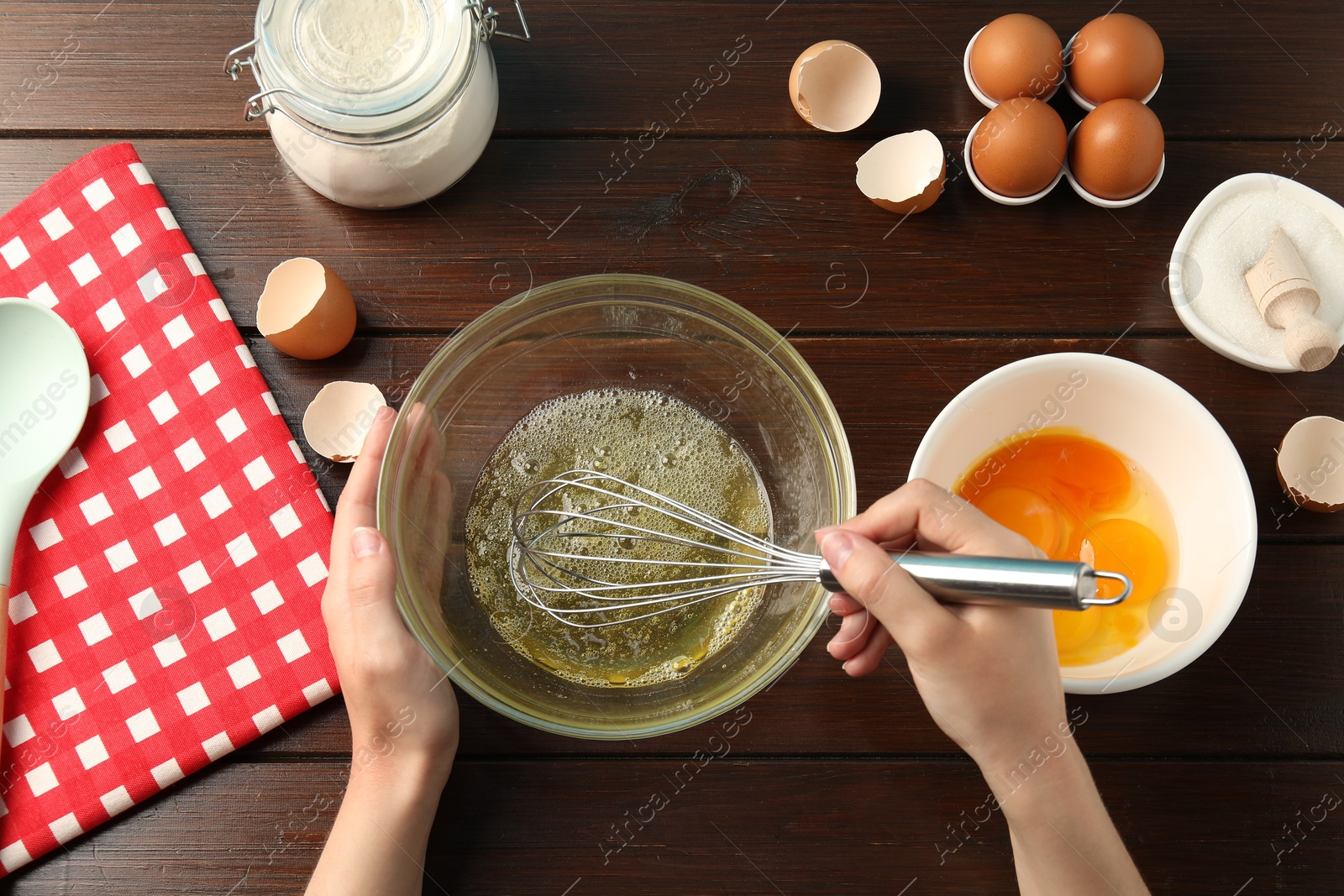 Woman whisking egg whites in bowl at wooden table, top view Photo of Woman whisking egg whites in bowl at wooden table, top view