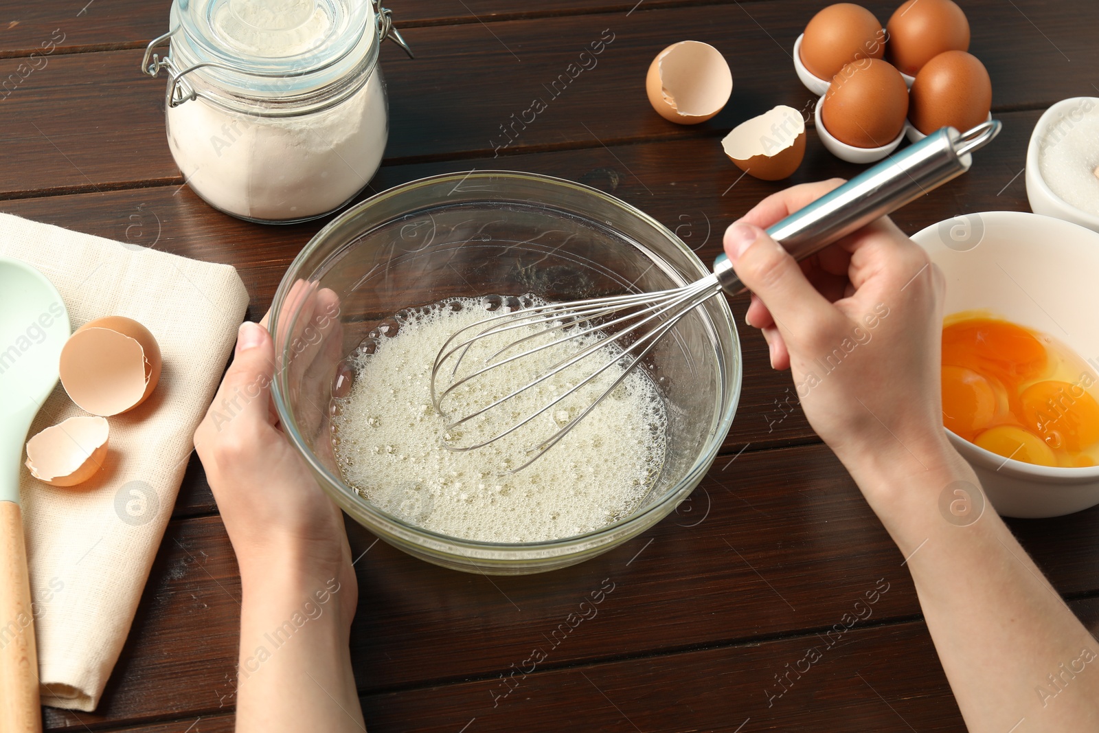 Woman whisking egg whites in bowl at wooden table, closeup Photo of Woman whisking egg whites in bowl at wooden table, closeup