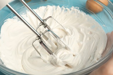 Photo of Whisking cream with hand mixer table, closeup