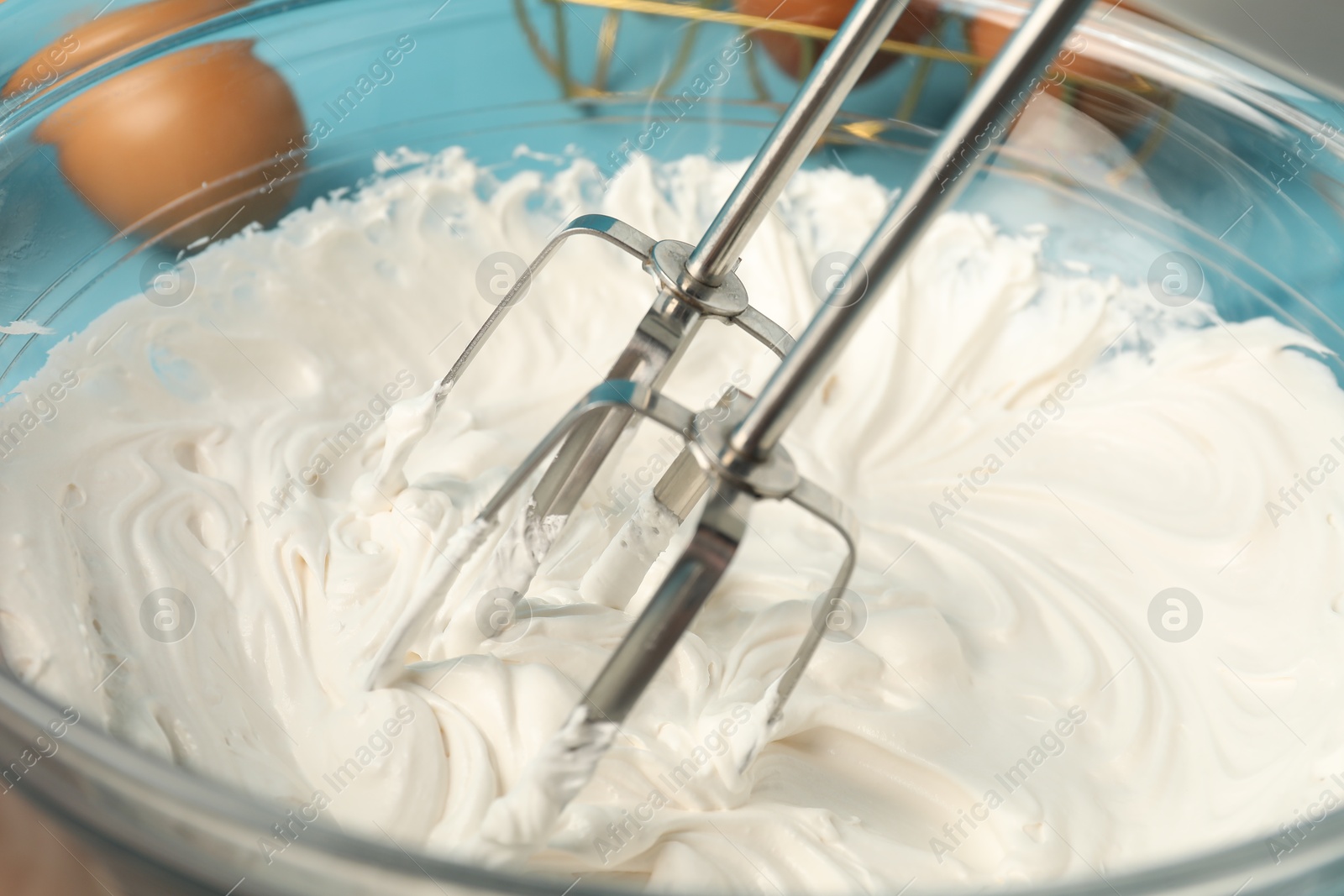 Whisking cream with hand mixer at table, closeup Photo of Whisking cream with hand mixer at table, closeup