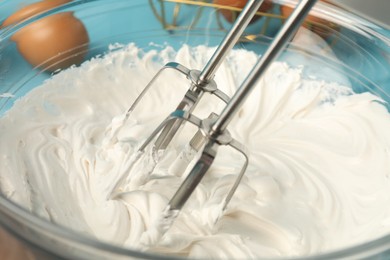 Photo of Whisking cream with hand mixer at table, closeup