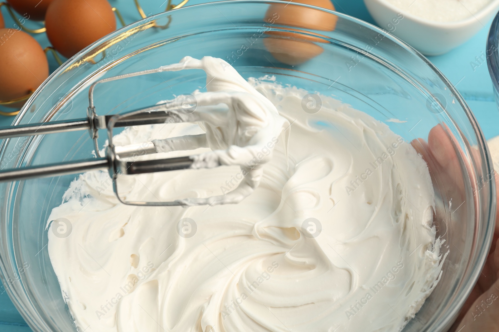 Whisking cream with hand mixer at table, closeup Photo of Whisking cream with hand mixer at table, closeup