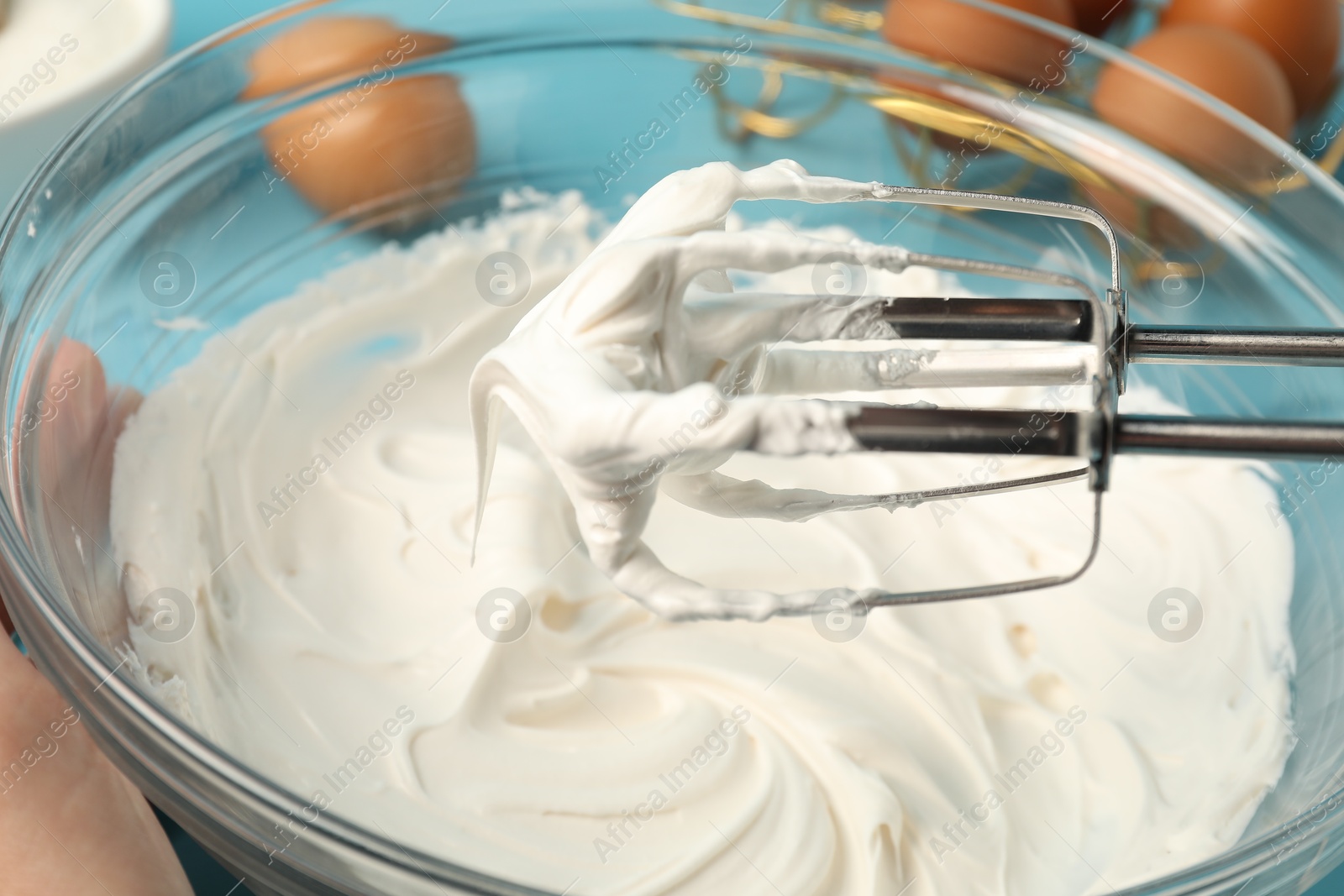 Whisking cream with hand mixer at table, closeup Photo of Whisking cream with hand mixer at table, closeup