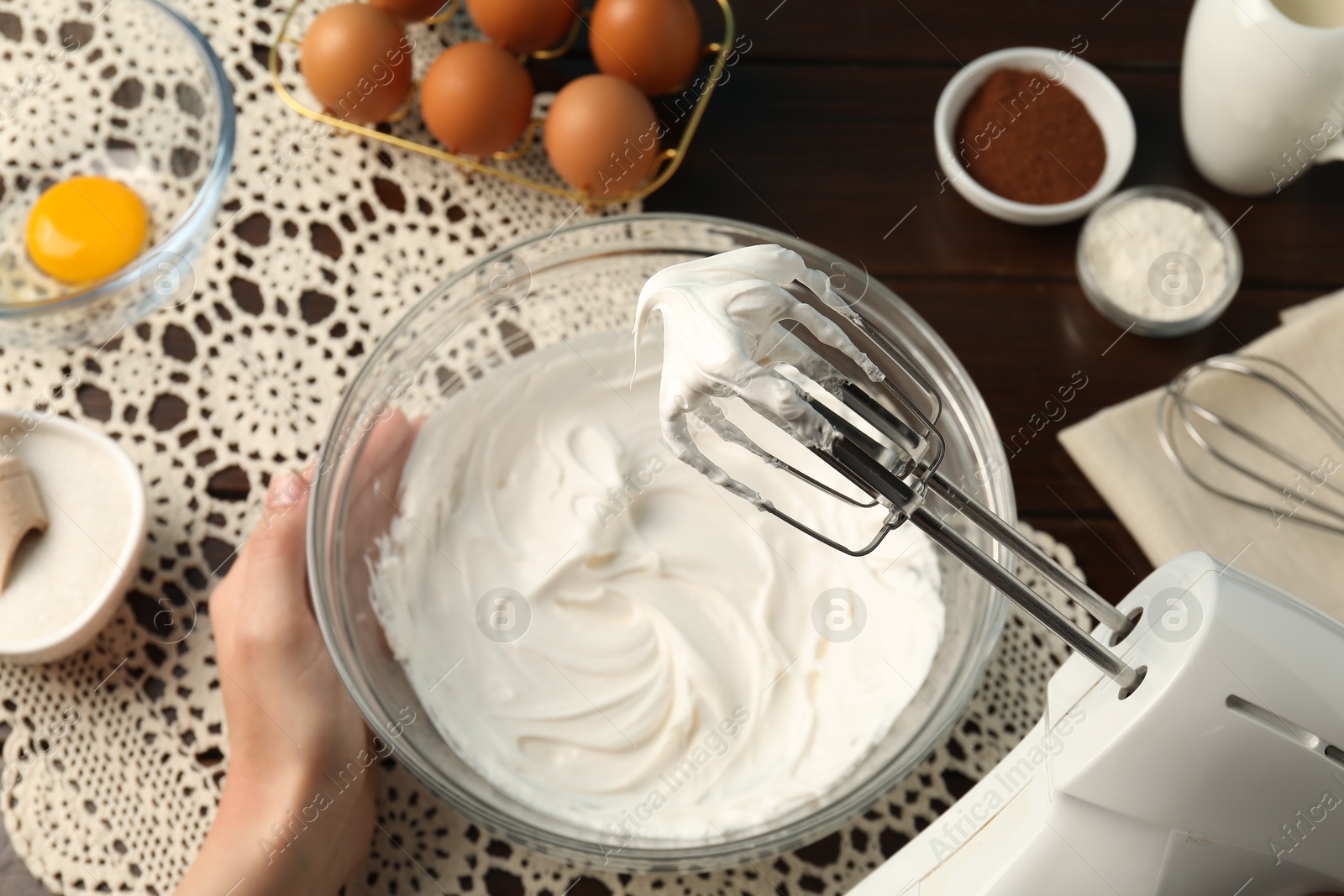 Woman whisking cream with hand mixer at table, top view Photo of Woman whisking cream with hand mixer at table, top view