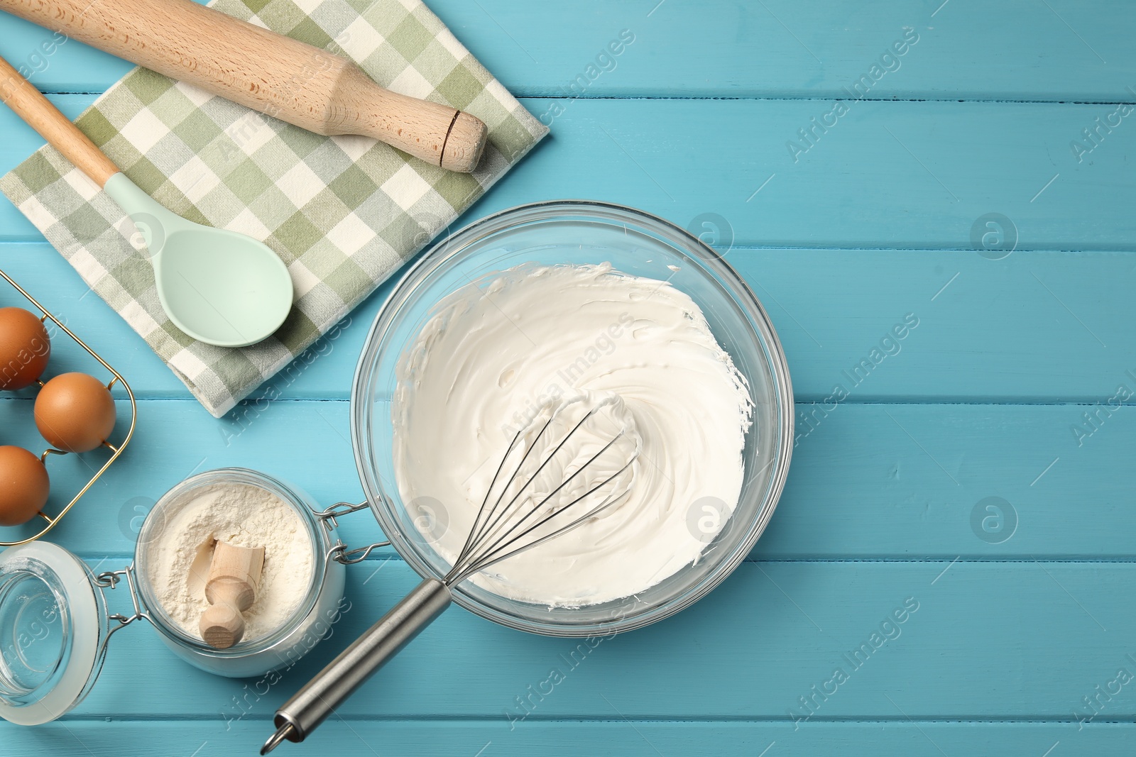 Whisk, whipped cream in bowl, eggs and flour on light blue wooden table, flat lay Photo of Whisk, whipped cream in bowl, eggs and flour on light blue wooden table, flat lay