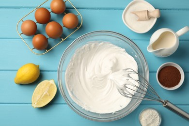 Photo of Whisk with whipped cream, eggs and other products on light blue wooden table, flat lay