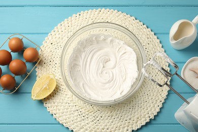 Photo of Hand mixer with whipped cream, eggs and other products on light blue wooden table, flat lay