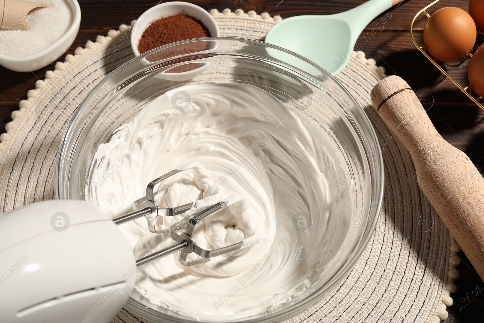 Hand mixer with whipped cream, eggs and other products on table, above view Photo of Hand mixer with whipped cream, eggs and other products on table, above view