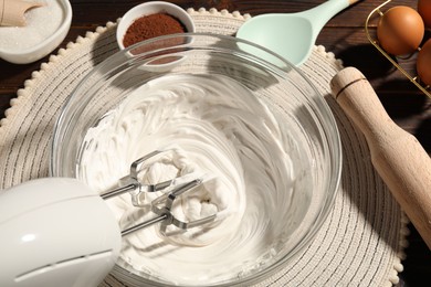 Photo of Hand mixer with whipped cream, eggs and other products on table, above view