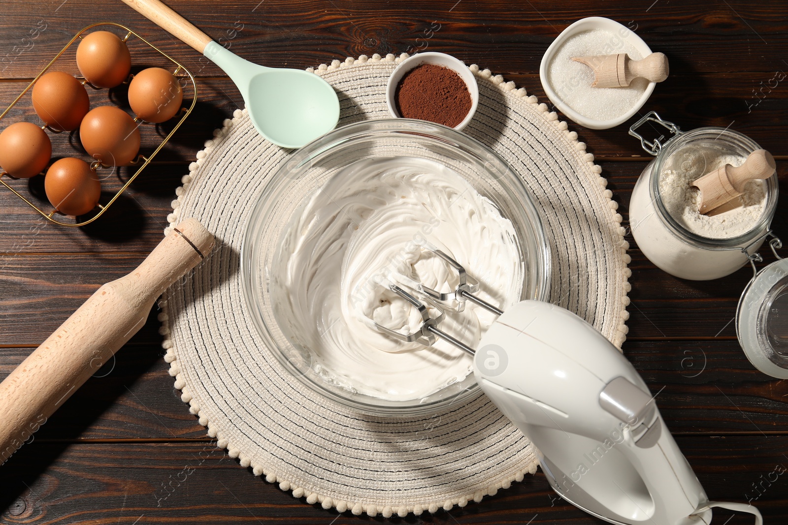 Hand mixer with whipped cream, eggs and other products on wooden table, flat lay Photo of Hand mixer with whipped cream, eggs and other products on wooden table, flat lay