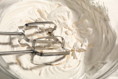 Photo of Whisks and whipped cream in bowl on table, top view